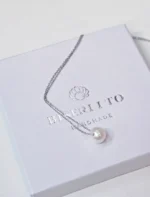 one-pearl ogrlica s jednim riječnim biserom položena na kutiju za nakit